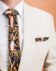 Stylish tie crafted from cotton, adorned with leafy designs in tones of burnt orange, sage green, and terracotta on a black background