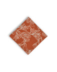 Chic pocket square with a burnt orange base, adorned with white outlines of the unique Kangaroo Paw flower, perfect for adding a pop of color to formal attire