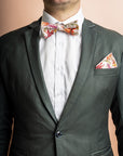 Bow tie featuring a detailed botanical print with green, yellow, and orange leaves and foliage, highlighting the diversity and beauty of various plant species on a dark background