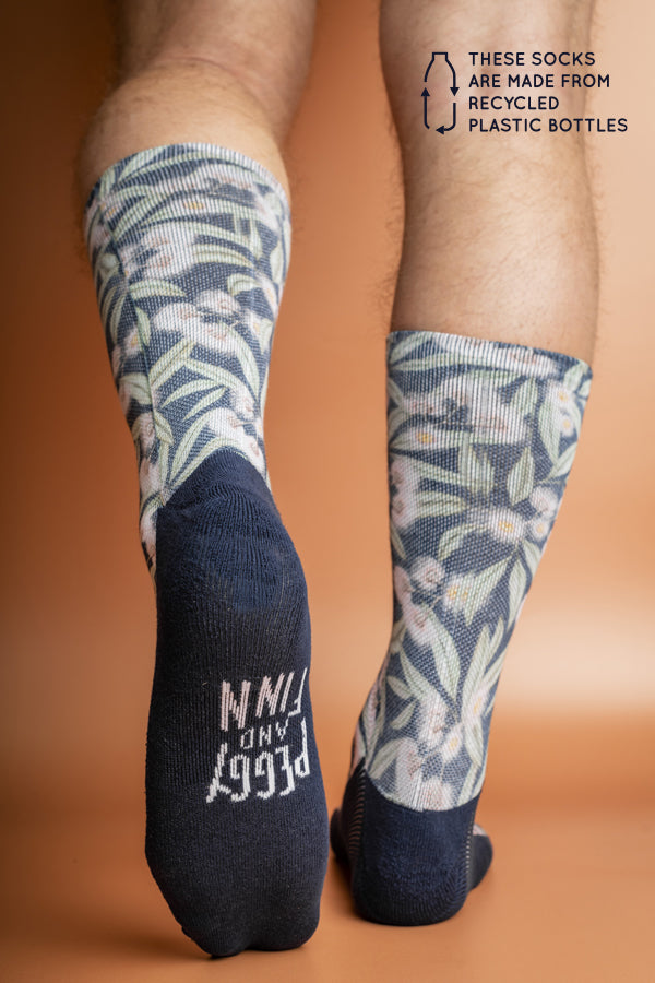 Soft and durable socks crafted from recycled bottles, decorated with a vibrant print of pink Flowering Gum blossoms against a blue background