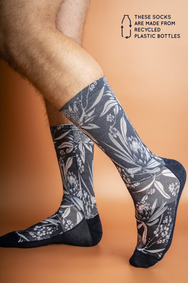Sustainable socks made from recycled materials, adorned with a pattern of iconic Australian flora against a navy background